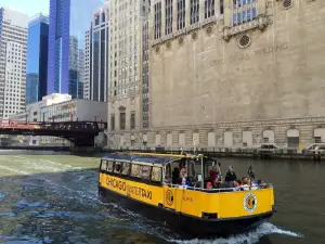 a yellow boat in the water with a city in the background