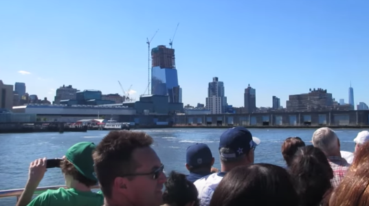 a group of people on a boat in front of a body of water with the city in the background