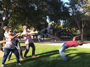 people outside pointing finger guns at someone pretending to dodge the bullets