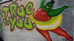 a large brick wall painted white with graffiti on it reading "True to you"