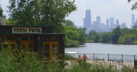 a small restaurant on the water with a patio and a city view to the right