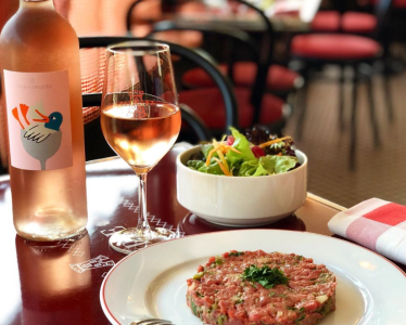 a table with a bottle of wine, a glass of wine, a bowl of salad and a plate with food on it