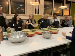 a group of people standing around a long table cooking