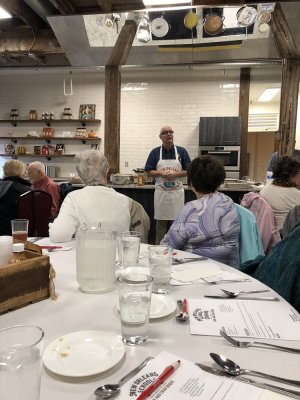 a group of people sitting at a table in a restaurant listening to a man speak