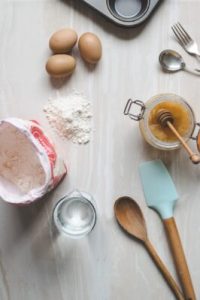 a wooden table with honey, eggs, flour, and more