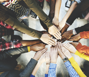 Hands on top of each other, different skin colors, different sleeves, all together for a team!