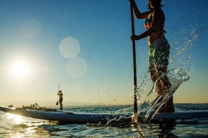 paddleboarder making a splash with their paddle at sunset