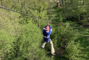 a guy with red helmet on ziplining in the forest