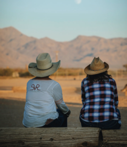 two people wearing cowboy hats looking out at the view of the ranch