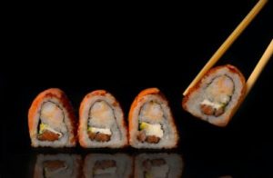 chopsticks picking up one of four pieces of sushi