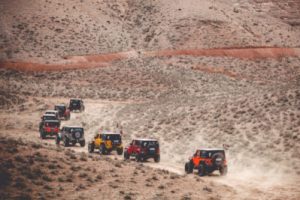 a line of Jeeps going up a barren dessert sandy road