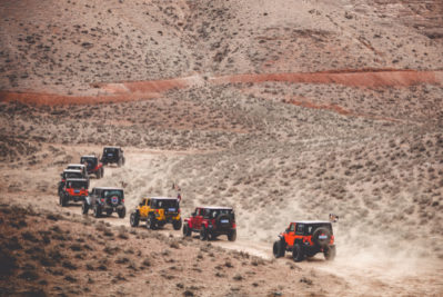 a line of Jeeps going up a barren dessert sandy road a line of Jeeps going up a barren dessert sandy road