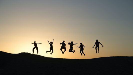 a group of people jumping in the sunset