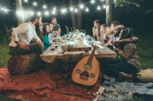 a group of people sitting at a table with strung lights up and an instrument