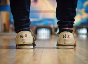 the back of bowling shoes standing by the bowling lane, with pins in the background