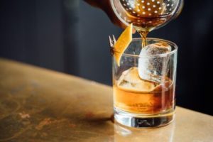 a cocktail shaker pouring a drink into a glass