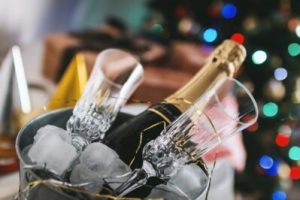 a bottle of champagne in a bucket in front of a christmas tree