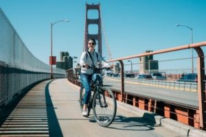 a woman biking over the san francisco bridge