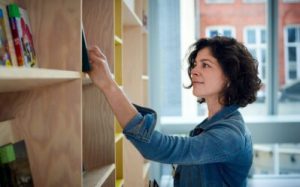 a woman looking on a book shelf