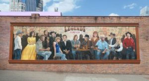 a mural of a group of country legends sitting together on the side of a building