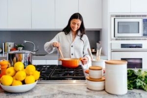 a woman cooking in her kitchen with a stack of lemons and white jars
