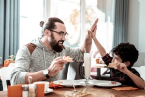 A father and son high fiving while eating at a restaurant