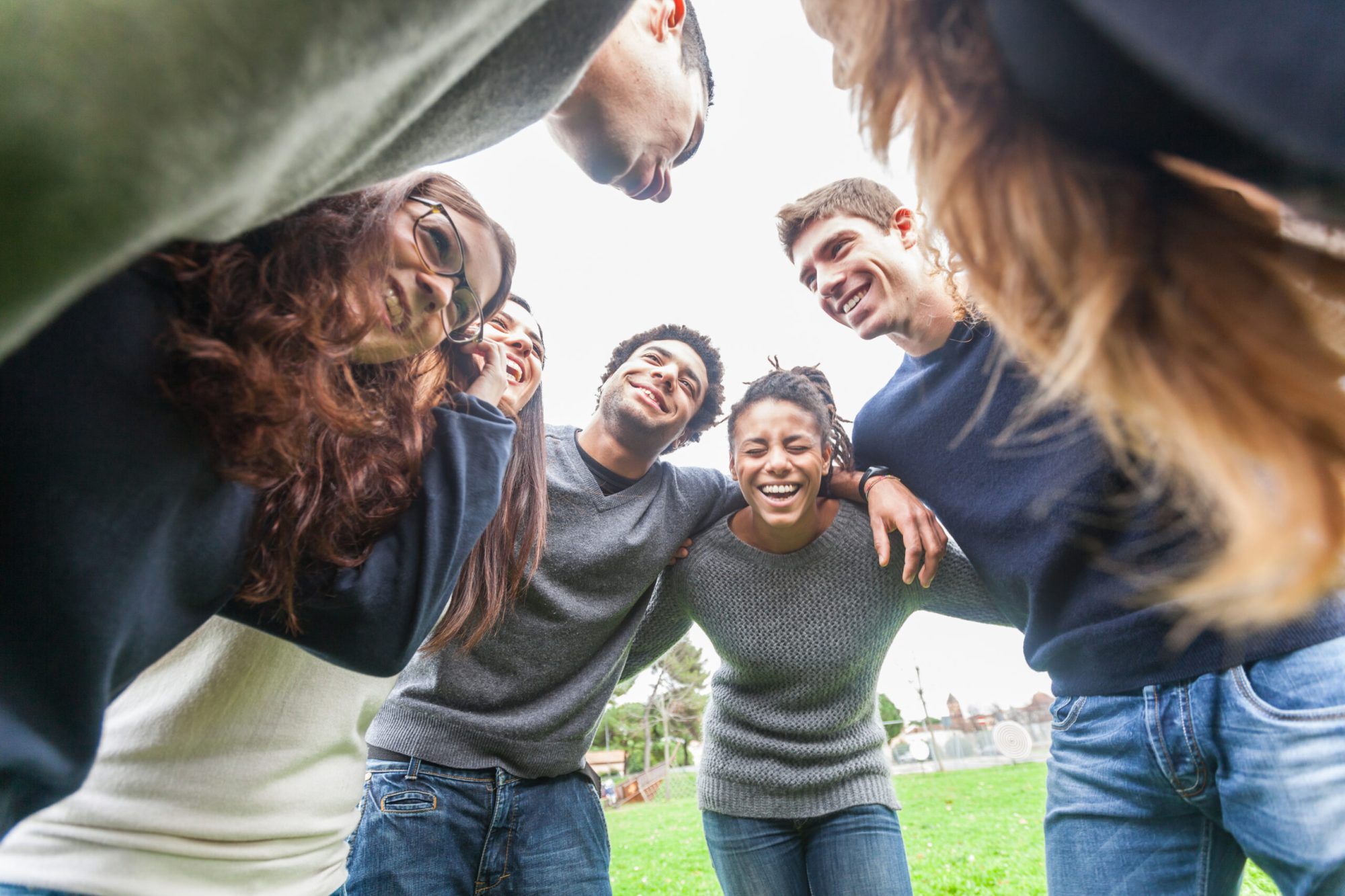 Multiracial group of friends embraced in a circle Multiracial group of friends embraced in a circle
