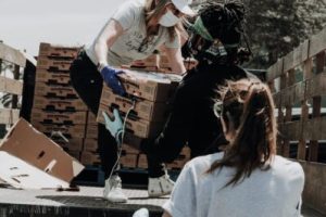 a person handing a stack of pizza boxes to someone else unloading a truck.