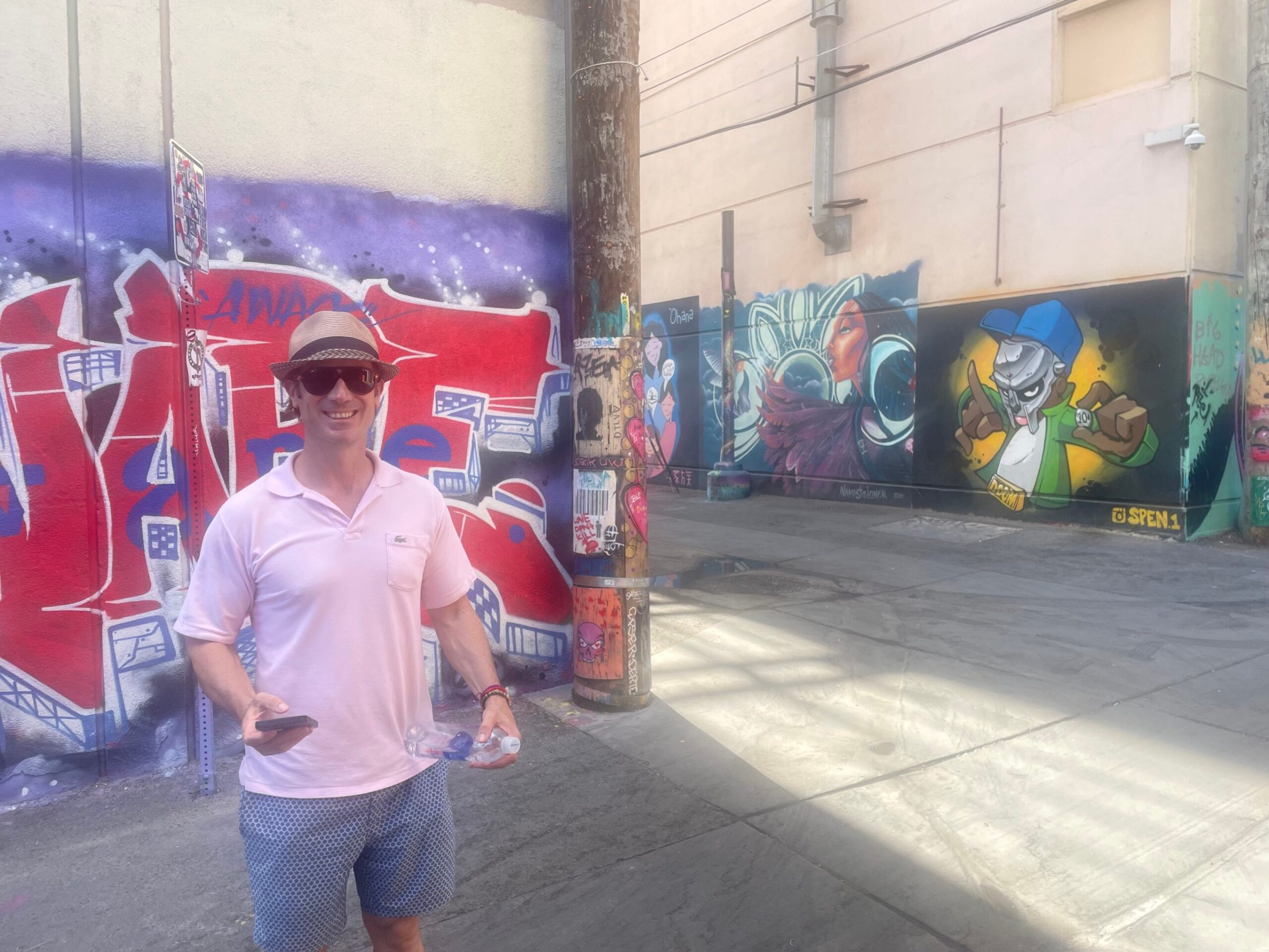 a man standing next to a graffiti covered wall