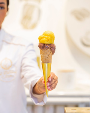 a hand holding an ice cream cone with a gold tip