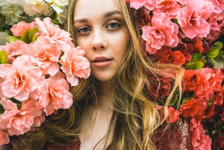 A girl posing with peach and pink flowers around her 