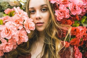 A girl posing with peach and pink flowers around her