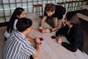 a group of people sitting at a table, Man in Black Crew Neck T-shirt Sitting Beside Woman in Gray and Black Stripe T