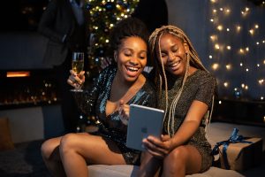 Two women taking a selfie while dressed up in sparkly outfits at night
