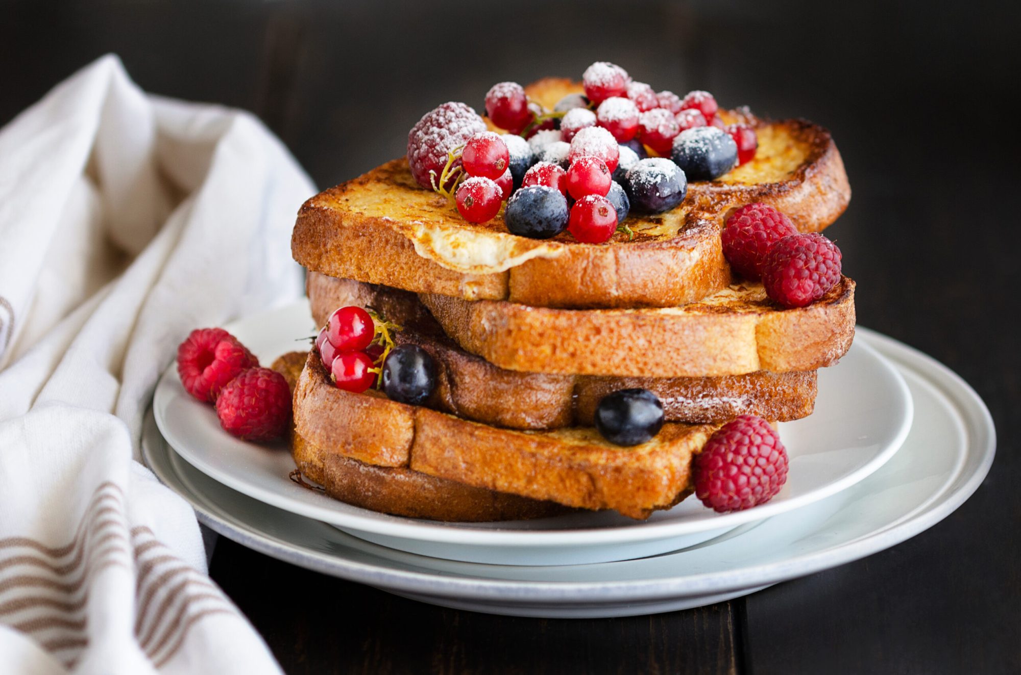 Traditional French toast with berries: blueberries, currant, raspberries and icing sugar for perfect sweet breakfast. Delicious dessert background.