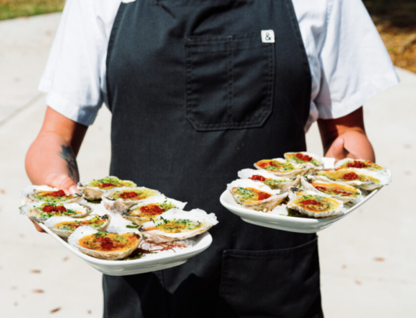 a person holding two plates of oysters