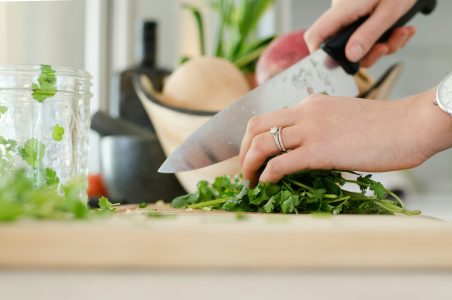 a person cutting a piece of broccoli