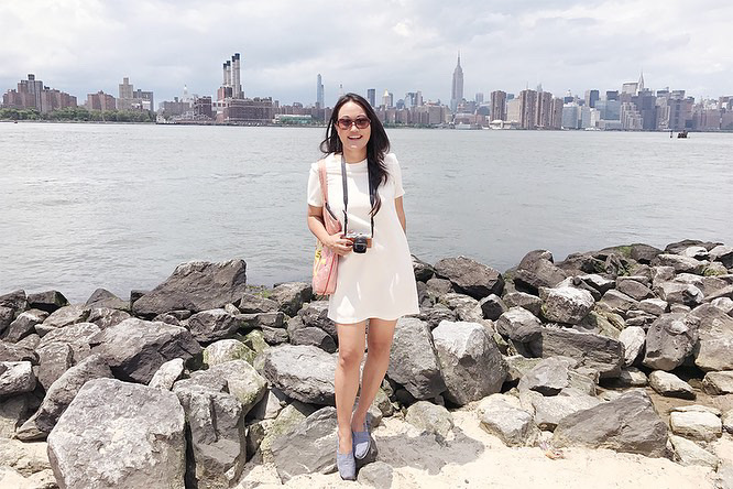 a woman standing in a rocky area next to a body of water