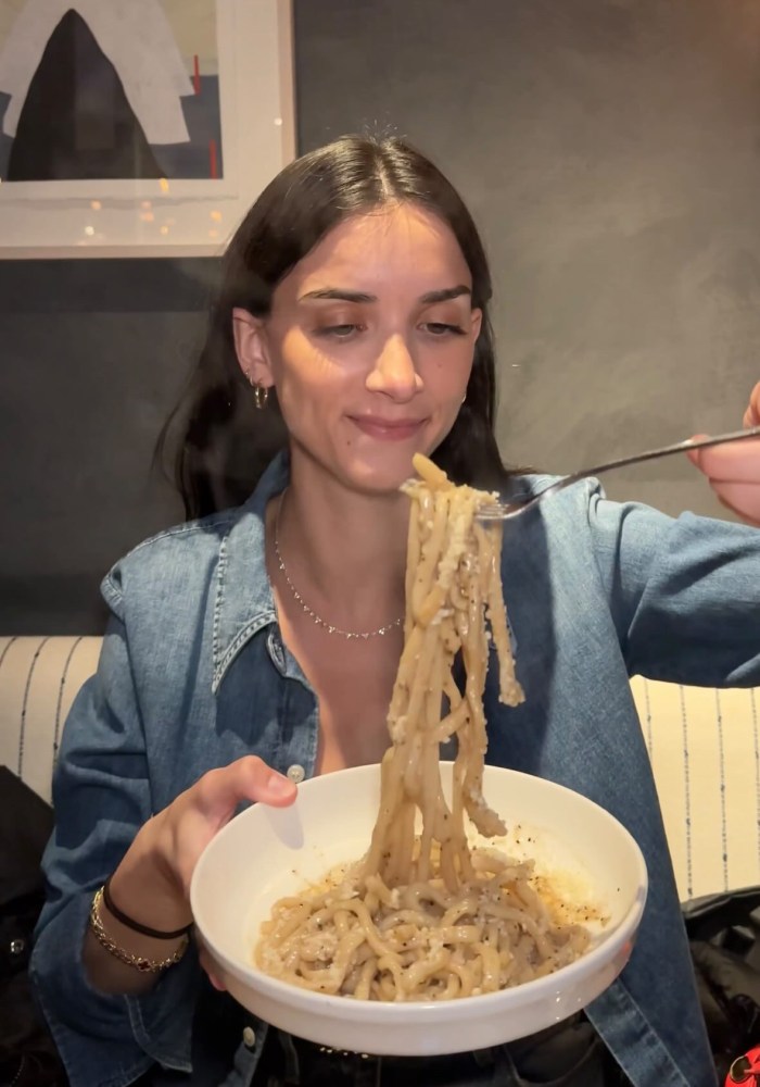 a woman sitting at a table with a bowl of pasta