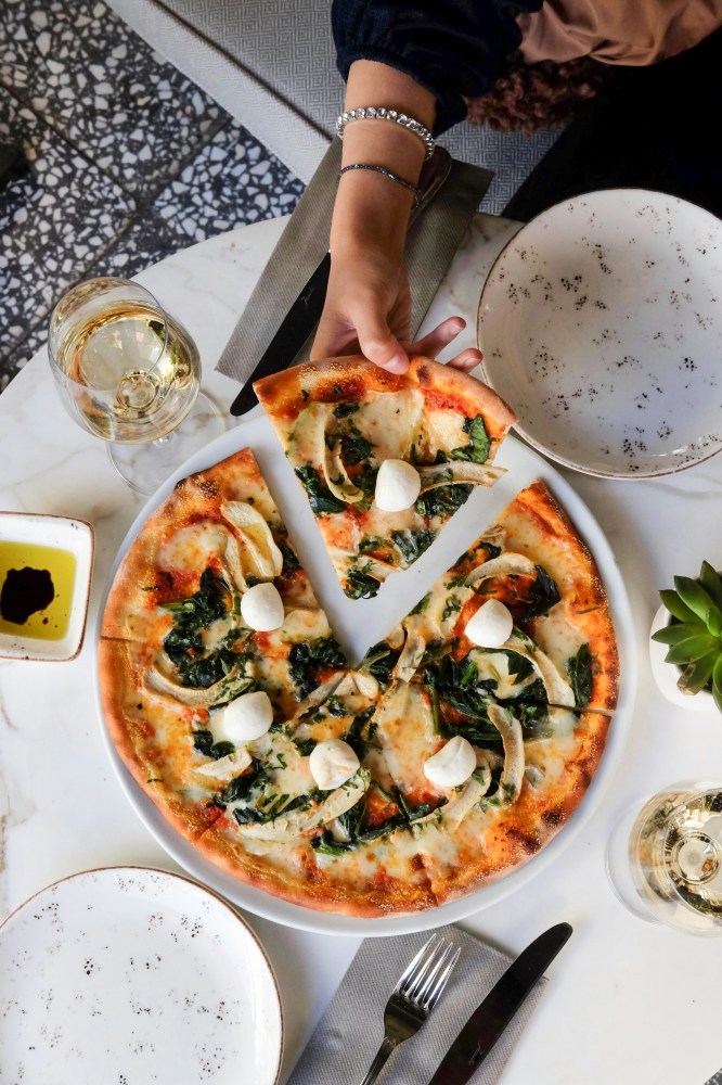 a person sitting at a table with a pizza