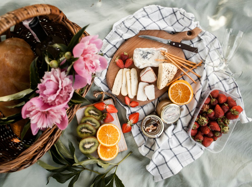 a beautiful picnic of cheeses and fruit laid out on a blanket