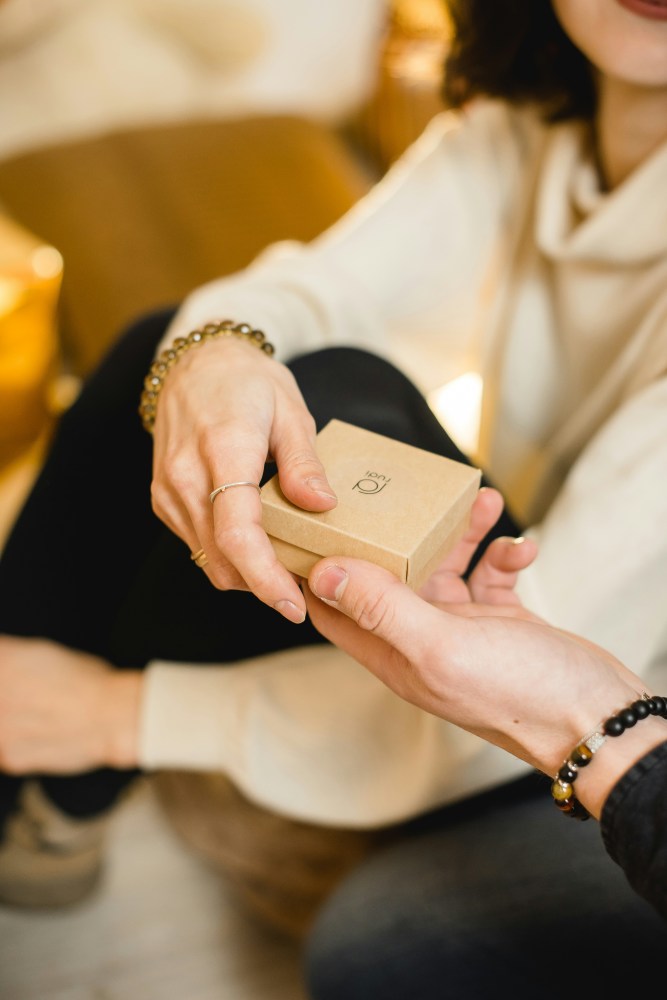 a person handing a woman a small gift box