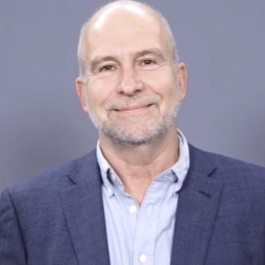 a man wearing a suit and tie smiling at the camera