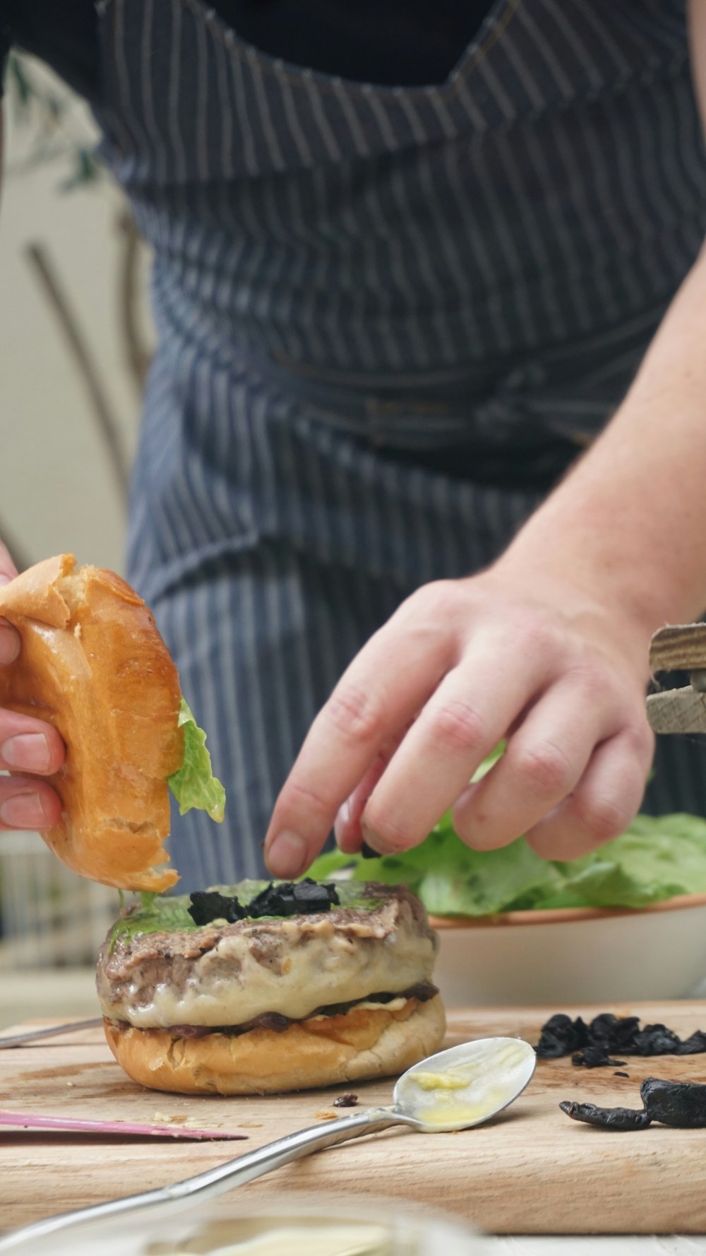 a person adding a secret ingredient to a burger