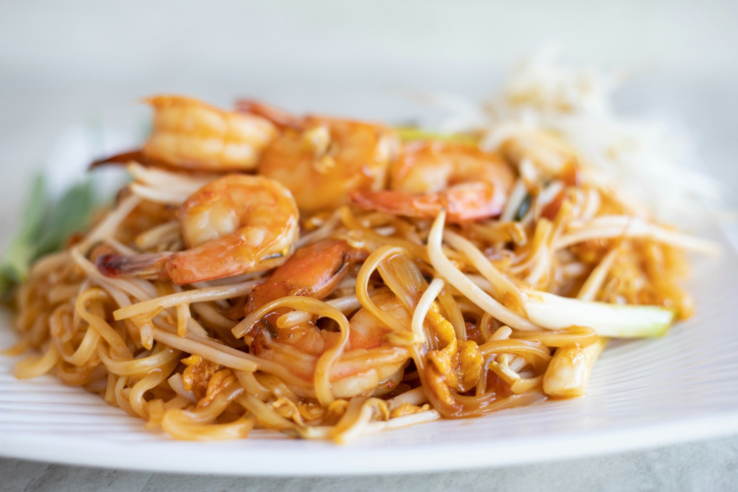 Plate of pad thai with shrimp, noodles, and bean sprouts.