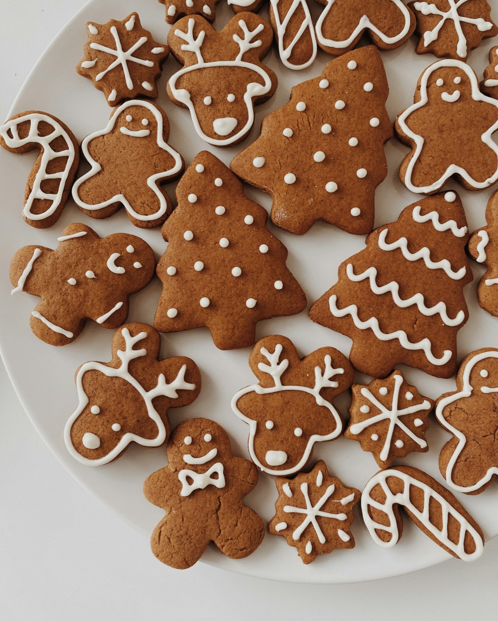 Assorted gingerbread cookies with icing on a white plate.
