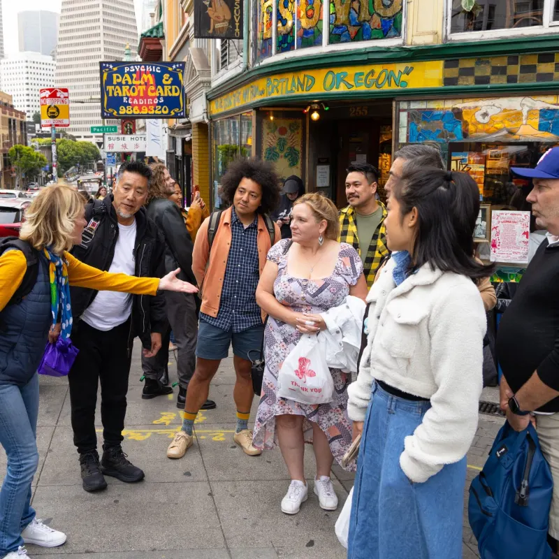 Group of people interacting on a colorful city street corner.