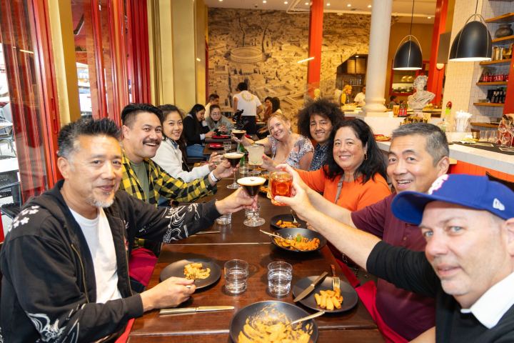Group of people at a restaurant table raising glasses in celebration.