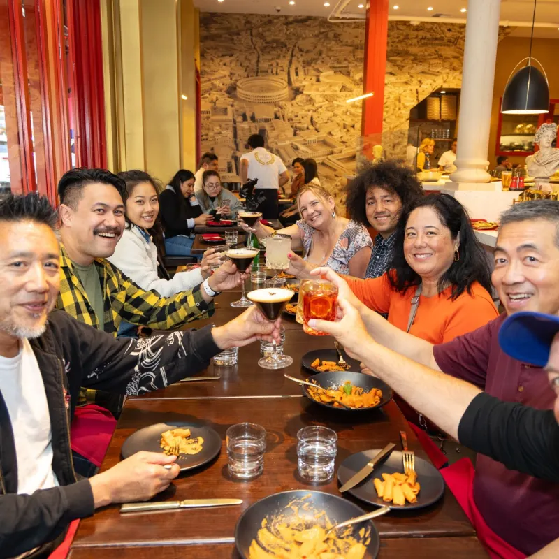 Group of people at a restaurant table raising glasses in celebration.