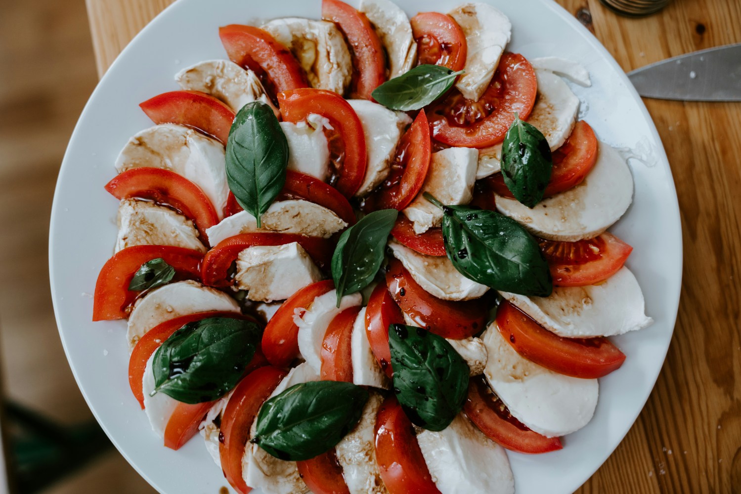 Caprese salad with tomatoes, mozzarella, and basil on a white plate.